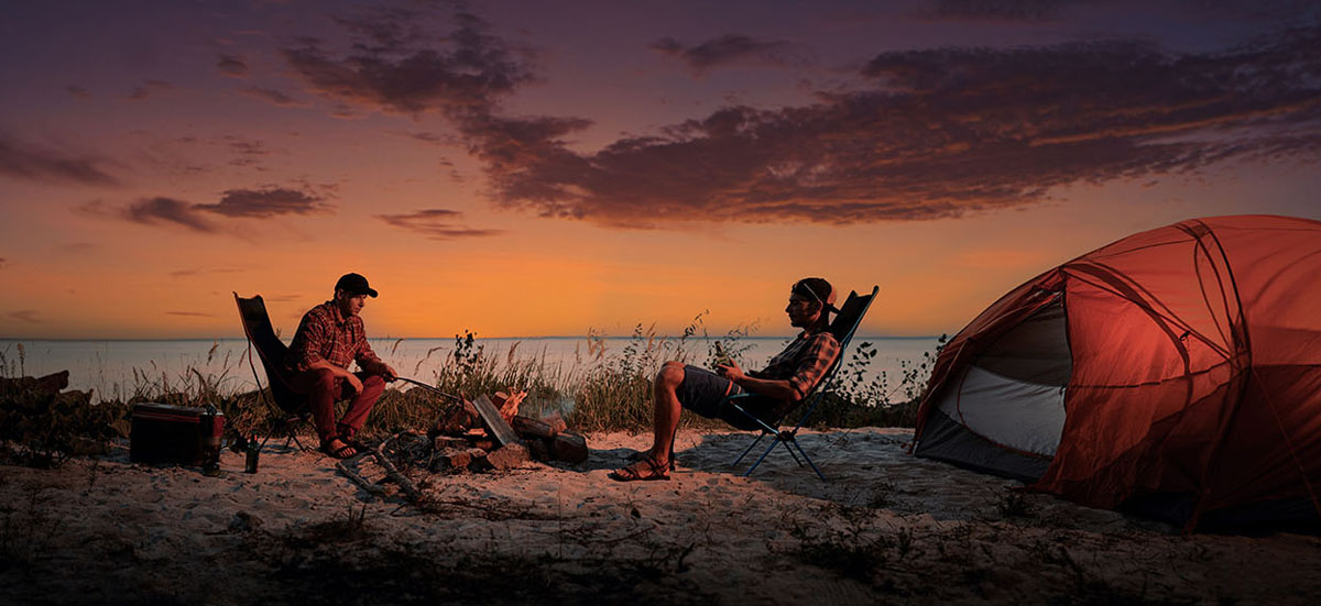 two guys sitting around a campfire