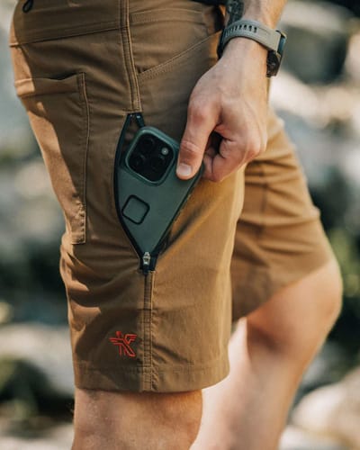 Man wearing shorts putting mobile phone in a side pocket
